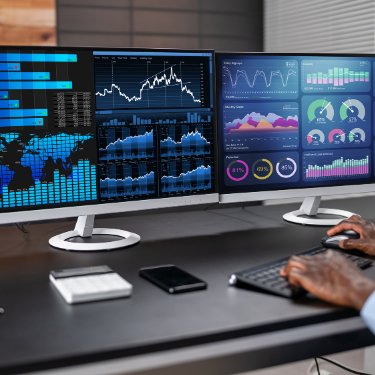 An employee looking at dashboards on two monitors